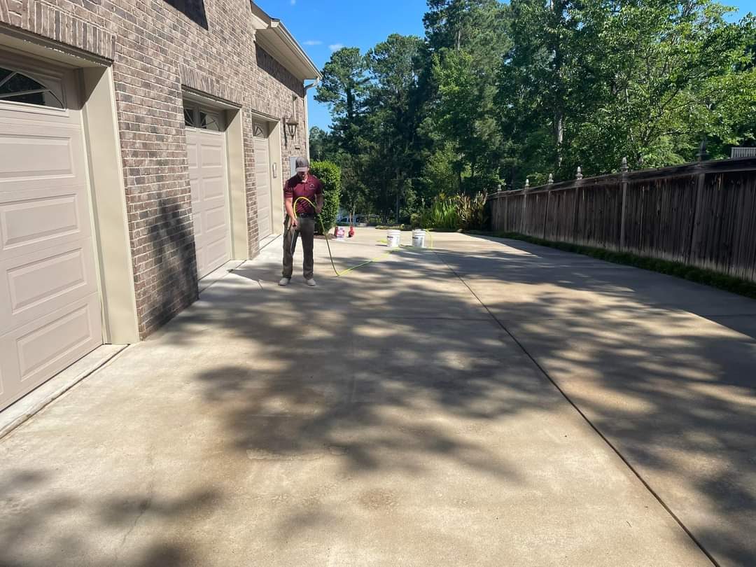 Jeremy surface-cleaning a concrete driveway in front of a brick garage
