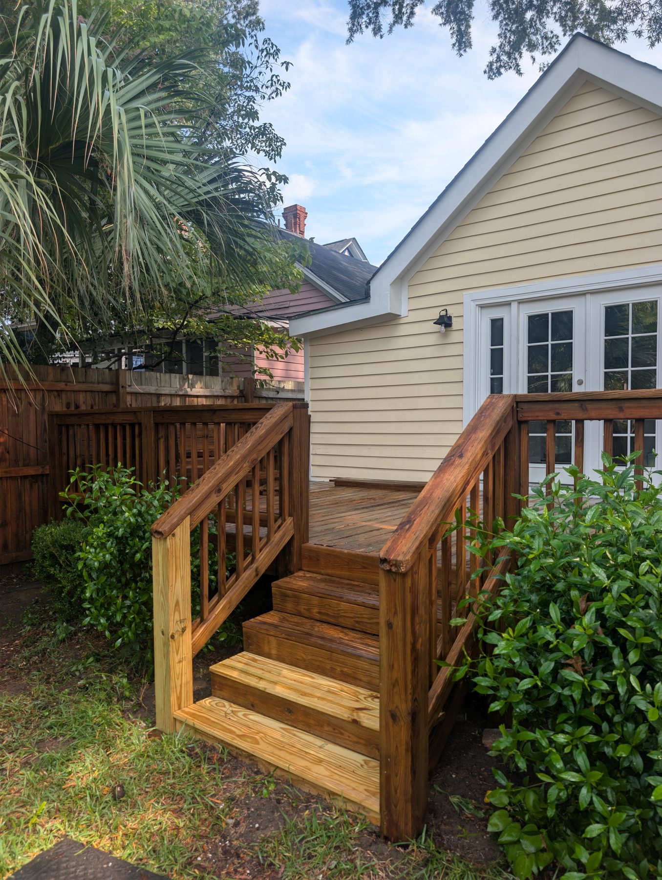 Wood deck steps and rail at the back of a house, cleaned and brightened to their natural color