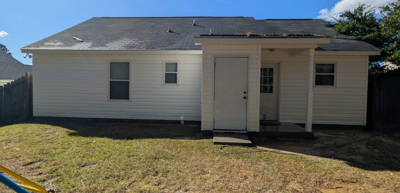The same white vinyl house after a soft wash, siding bright and even