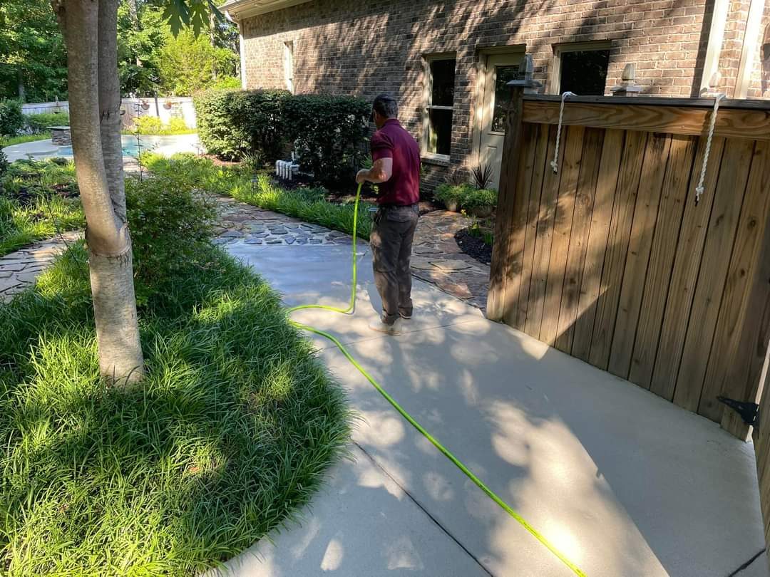 Jeremy cleaning a paver driveway beside a brick house
